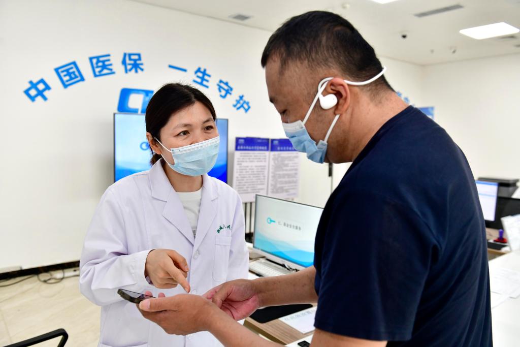 2025年8月21日，在山东省郓城县人民医院医保便民服务站，工作人员帮助居民办理医保业务。新华社记者 郭绪雷 摄 