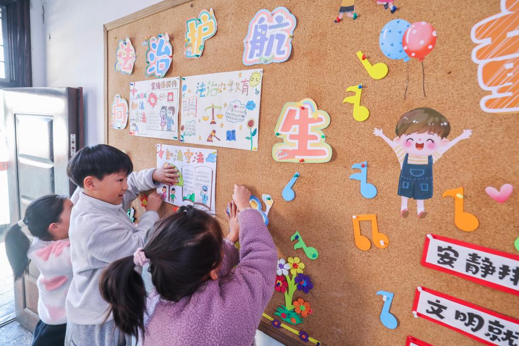2025年12月9日，浙江省诸暨市暨南街道中心学校王家井小学的学生把自己创作的法治宣传画贴到教室的宣传栏中。新华社记者 徐昱 摄