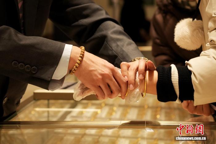 近日，消费者在北京菜市口百货股份有限公司试戴金饰。受国际金价波动等因素影响，黄金产品受消费者关注。　中新社记者 张祥毅 摄 
